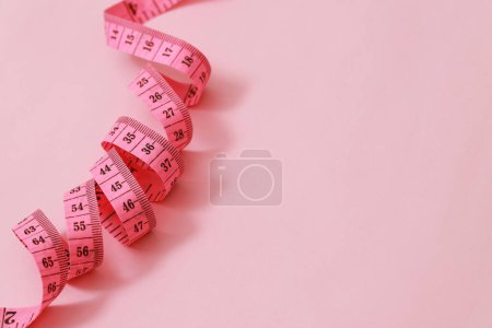 tape measure for obese people on a pink background soft focus