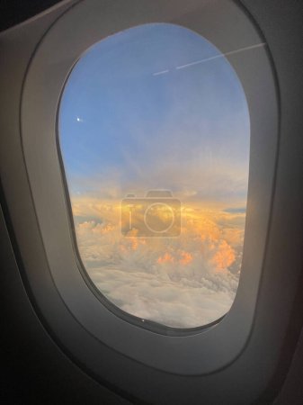 Photo for Looking out airplane window into sunset in the clouds - Royalty Free Image