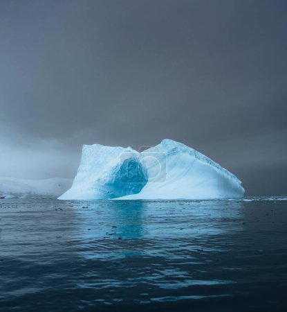 Foto de Iceberg fotogénico e intrincado con un agujero bajo un cielo interesante y colorido durante. Calentamiento global y concepto de cambio climático. Foto tomada en la Antártida, círculo ártico de Groenlandia. Foto tomada en - Imagen libre de derechos
