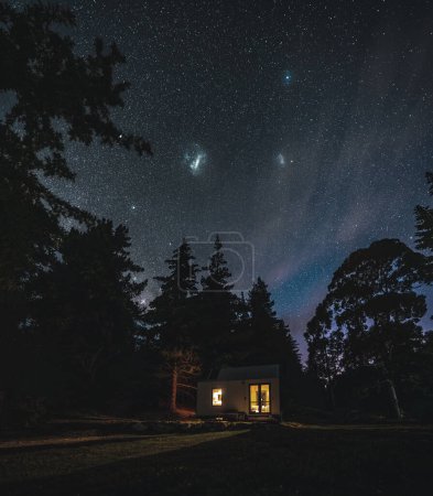 Cottage against the night sky with the Milky Way. Southern sky. Trees and forest. Magical scene. South Island, New Zealand. Photo taken in New Zealand.