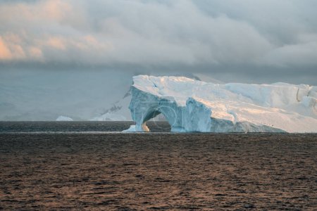 Téléchargez les photos : Un iceberg flottant dans la péninsule antarctique, l'antarctique et le Groenland arctique. Le réchauffement climatique et le concept de hasard climatique. Iceberg avec trou. Photo prise en Antarctique. - en image libre de droit