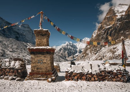 Foto de Banderas de oración y el monte Annapurna en el fondo. Cielo azul y paisaje de nieve. Campamento Base Annapurna, Nepal - Imagen libre de derechos