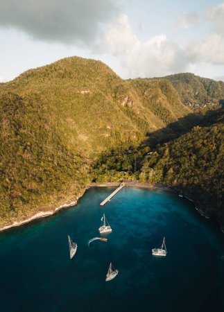 Panoramic aerial drone picture of Anse darlet in Martinique, Caribbean island, with sailboats, turquoise water and cloudy blue sky in background. Photo taken in Martinique.