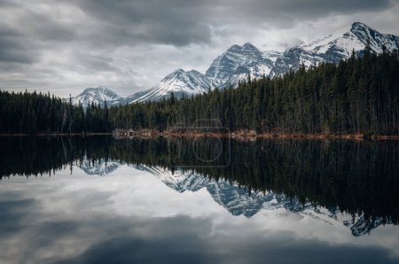 Foto de Lago Herbert en Alberta, Canadá en un día nublado con impresionantes montañas y reflejos de agua. - Imagen libre de derechos