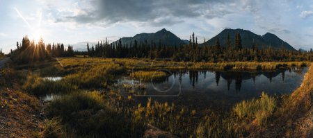 Téléchargez les photos : McCarthy Road view, McCarthy valley, Wrangell St. Elias National Park, Alaska. Prairie et montagnes avec un lac au coucher du soleil. Paysage toundra - en image libre de droit
