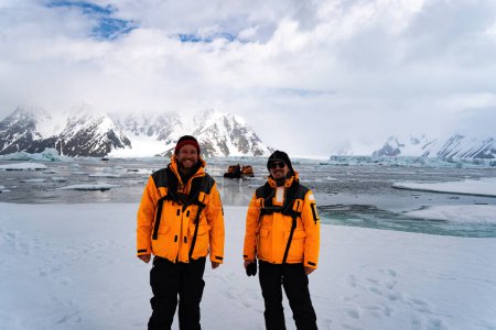 Foto de Joven Turista Masculino con chaqueta amarilla en la Antártida sonriendo. Icebergs en segundo plano. Senderismo con mochila en las montañas, Antártida. - Imagen libre de derechos