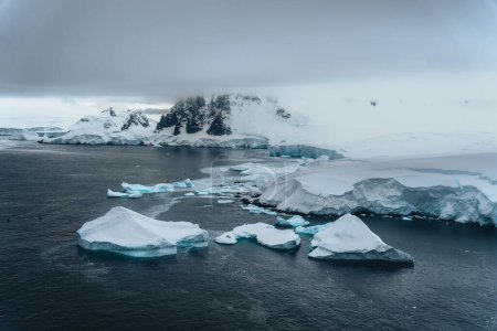 Foto de Panorama montañoso de la costa Antártica. Increíble vista panorámica. Los pedazos del hielo flotando en el océano congelado. Impresionante paisaje de invierno en los tonos azules. Viajes, naturaleza, destino
. - Imagen libre de derechos