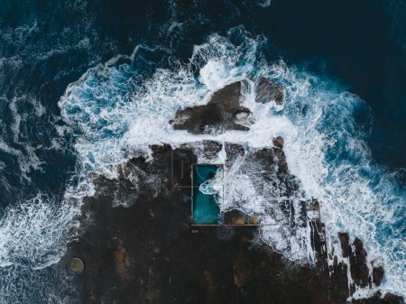 Foto de Vista aérea a primera hora de la mañana con olas del océano que fluyen sobre la piscina de roca. Ourie Pool, Gerringong. North Curl Curl piscina de roca oceánica durante la tormenta. Nueva Gales del Sur, Australia - Imagen libre de derechos