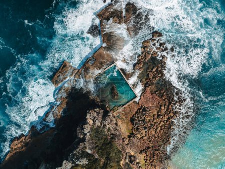 Vista aérea a primera hora de la mañana con olas oceánicas que fluyen sobre rocas alrededor de la piscina de rocas North Curl Curl Ocean durante la tormenta. Foto tomada en Australia.