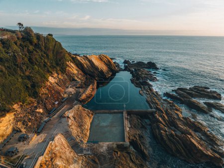 Aerial drone view of Blue Pool in Bermagui during sunrise sunset with blue sky and reflection. New South Wales, Australia.