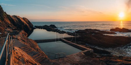 Aerial drone view of Blue Pool in Bermagui during sunrise sunset with blue sky and reflection. New South Wales, Australia.