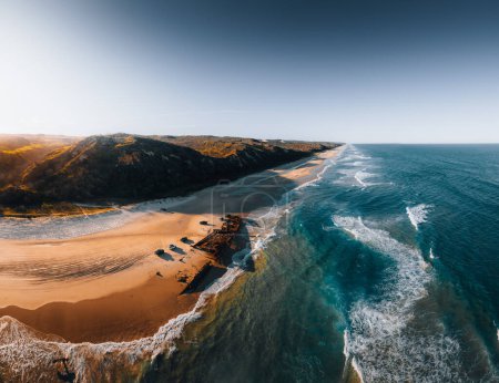 Photo for Kgari High angle aerial birds eye drone view of the Maheno shipwreck on Seventy-Five Mile Beach on Fraser Island, Queensland, Australia. Beautiful sunset light with waves - Royalty Free Image