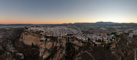 Téléchargez les photos : Paysage rocheux de la ville de Ronda avec pont Puente Nuevo et bâtiments, au lever du soleil en Andalousie, Espagne. - en image libre de droit