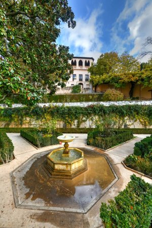 View of The Generalife courtyard, with its famous fountain and garden through an arch. Alhambra de Granada complex at Granada, Spain, Europe on a bright winter day.