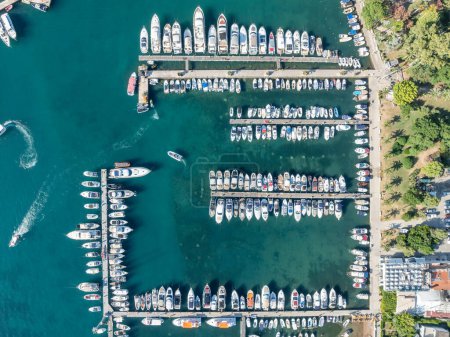 Aerial top down view of boat dock and yacht port in Budva, Montenegro. White private motor boats are moored to pier on Adriatic sea coast. Yacht club boats parking.