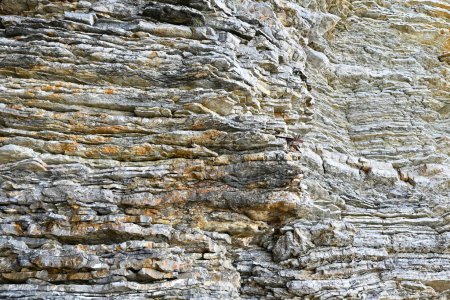 Textur aus geschichteten Mineralformationen auf einem Felsen in Budva, Montenegro. Geometrische abstrakte diagonale Linien in der Natur. Helles beige-gelbes Muster