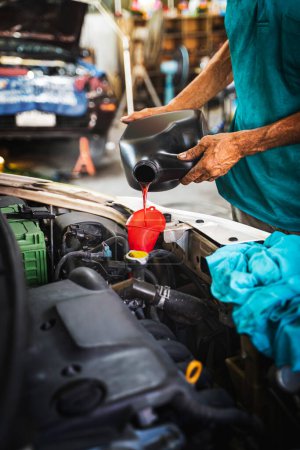 Foto de Mecánico Verter aceite al motor del coche en el garaje. - Imagen libre de derechos