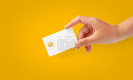 Téléchargez les photos : Femme Main tenant vierge carte de puce de crédit sur un fond jaune pour les entreprises et les finances - en image libre de droit