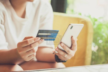 Téléchargez les photos : Main de femme utilisant le téléphone intelligent et tenant la carte de crédit pour le paiement d'achats en ligne, ou pour des concepts d'affaires, de finances, et de paiement. - en image libre de droit