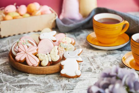 Téléchargez les photos : Esthétique Biscuits glacés de Pâques et tasse de thé sur la table de vacances décorée. - en image libre de droit