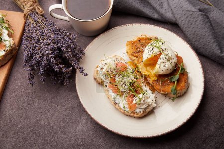 Foto de Desayuno estético - sándwiches con huevos, salmón, alfalfa, semillas de chía, guisantes germinados, taza de café. Flores de lavanda decoraciones acogedoras - Imagen libre de derechos