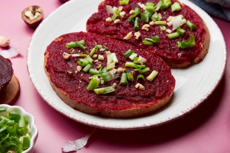 Close up of beetroot spread sandwiches with spring young onion, garlic and walnuts. Vegan healthy snacks food. Top view.