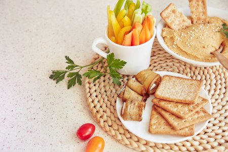 Hummus maison avec biscuits, persil et légumes frais sur la table. Snacks rustiques végétariens sains de près