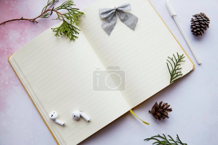 Photo for Seasonal Christmas mock up notepad with decorations, earphones in home office. New year resolution, new start and list of goals lifestyle. - Royalty Free Image