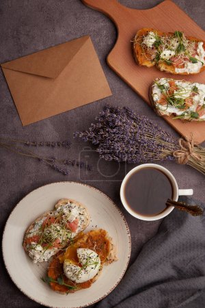 Photo for Morninhg table with sandwiches with Greek yogurt and zucchini spread, poached egg, salmon, envelope and bouquet of lavender - Royalty Free Image