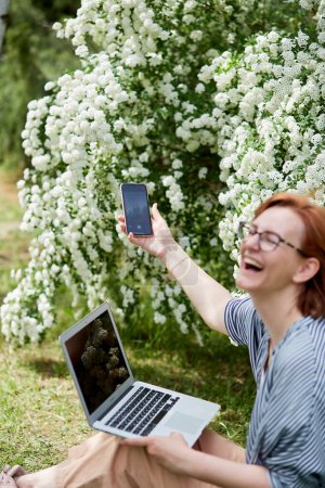 Photo for Nature's office - young professional red haired woman takes remote work to the scenic outdoors. - Royalty Free Image