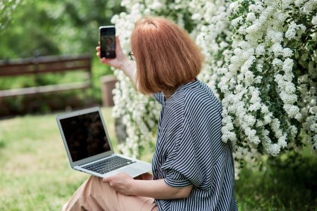 Photo for Freelance lifestyle, remote work in full bloom a young woman captures her moment among white flowers. - Royalty Free Image