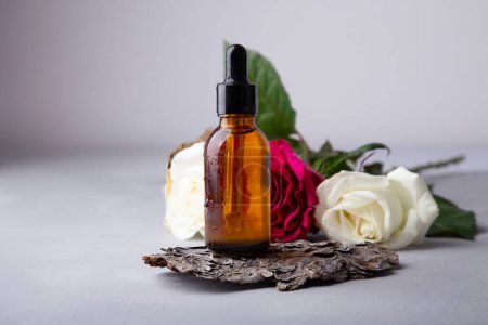 Minimalist beauty concept with organic serum and roses buds on rustic wood.