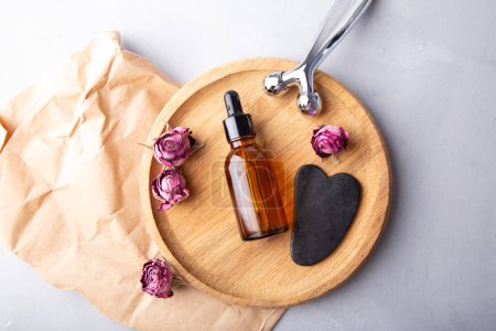 Serene beauty setting with gua sha, facial roller and essential oil for spa at home.