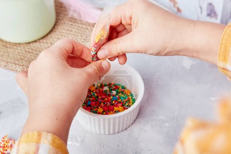 Süße Osterbräuche: Kinder verzieren Plätzchen mit Streuseln aus nächster Nähe.