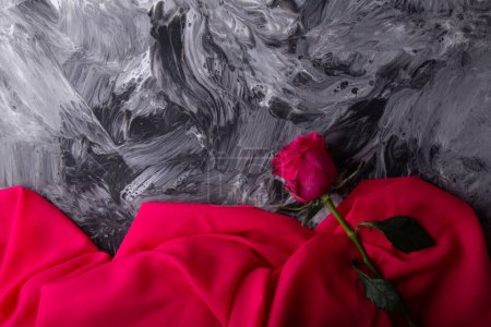 Classic rose over a swirling grayscale backdrop with a pop of red fabric.