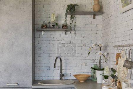 Urban chic kitchen corner with white brick wall, sink and natural decorations.