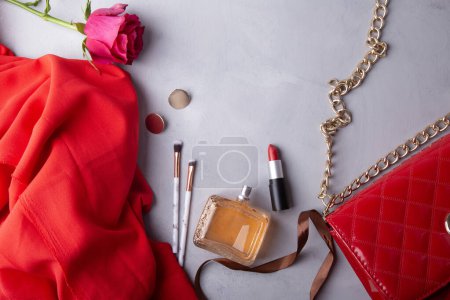 Esenciales femeninos perfume, lápiz labial, maquillaje pinceles y flores frescas.