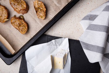 Frisch geschnittener Brie-Käse auf Schiefer mit goldbraunem Brot im Hintergrund.