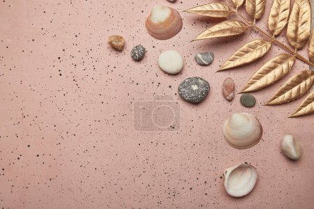 Summer background with golden leaves and seashells on pink sand with copy space.