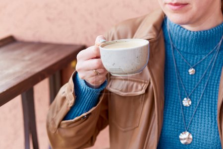 Téléchargez les photos : Gros plan femme avec manucure bleue tient une tasse de café avec cappuccino. - en image libre de droit