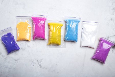 Regenbogenfarben von Sandkunststoffen in Kunststoffverpackungen auf strukturierter Oberfläche