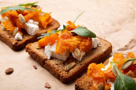 Photo for Gourmet pumpkin toast with feta and fresh herbs on a whole grain slice. Rustic food. - Royalty Free Image