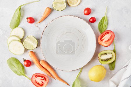 Ästhetisches, veganes, biologisches, gesundes Essen, pflanzliches Ernährungskonzept. Weißer Teller auf dem Tisch zwischen Gemüse und Obst .