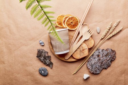 Natural aesthetic, eco-friendly flat lay. Organic wooden and paper cutlery, bark tree, pebbles with blurred foreground. Sustainable, zero waste, plastic free lifestyle on crumpled paper.