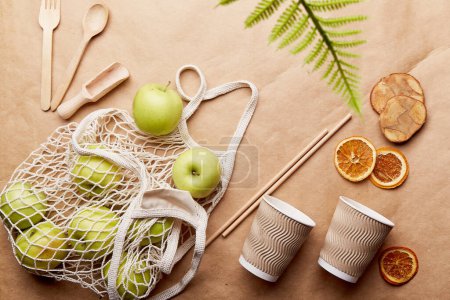 Eco shopping bag with apples, wooden cutlery on crafting paper. Sustainable lifestyle. Natural eco-friendly, zero waste tableware, blurred foreground