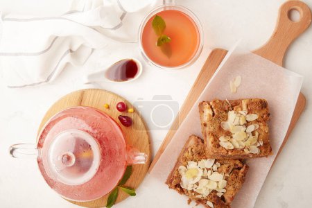 Ästhetisches Lagom home - warmer Zimtkuchen und Glasteekanne mit einer Tasse Preiselbeerhartriegel Naturtee..