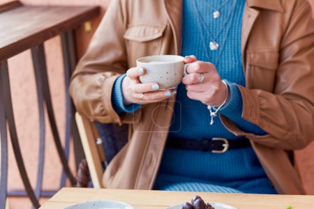 Téléchargez les photos : Femme en bleu avec manucure bleue tient une tasse de café avec cappuccino. - en image libre de droit