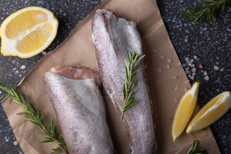 fish hake seasoned with herbs, pepper and lemon on a rustic wooden board, for recipes or seafood market displays