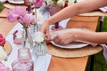 Elegant outdoor table setting with pink peonies. Wedding reception and event planning themes.