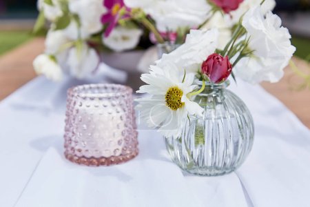 Pink candle and bouquet of flowers. Cozy and inviting atmosphere, summer picnic table setting.